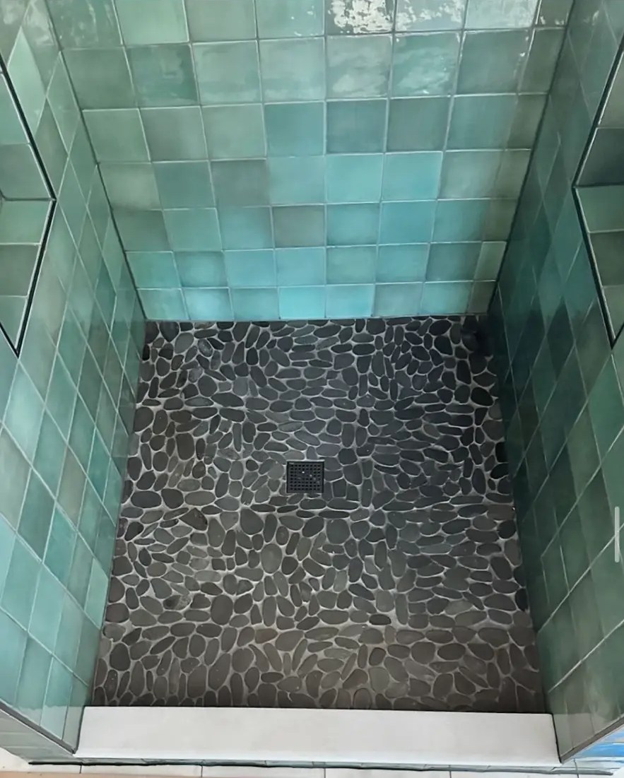 Black pebble tile shower pan with green square ceramic wall tile