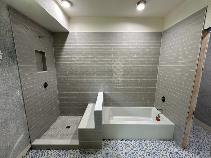 Gray subway tile tub and shower combo with patterned encaustic floor tile