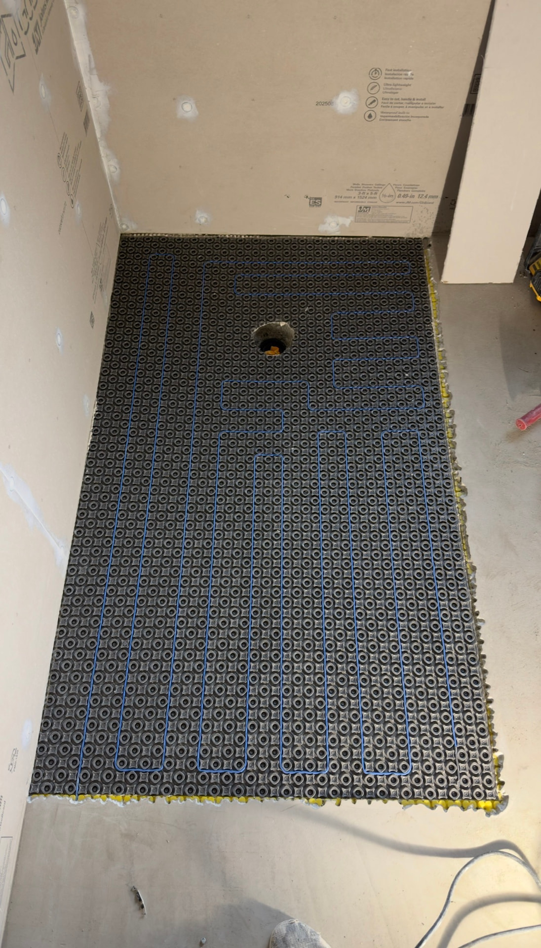 Heated floor cable routed through an uncoupling membrane around a toilet flange