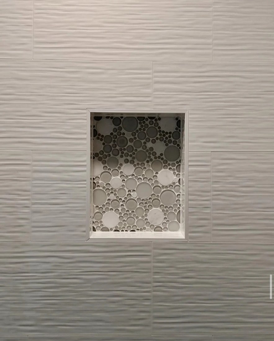 Textured white tile wall with a circular mosaic tile shower niche