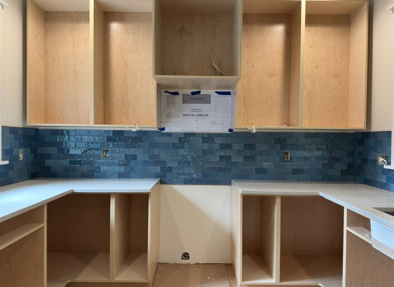 Blue glazed subway tile kitchen backsplash installed between counters and cabinets