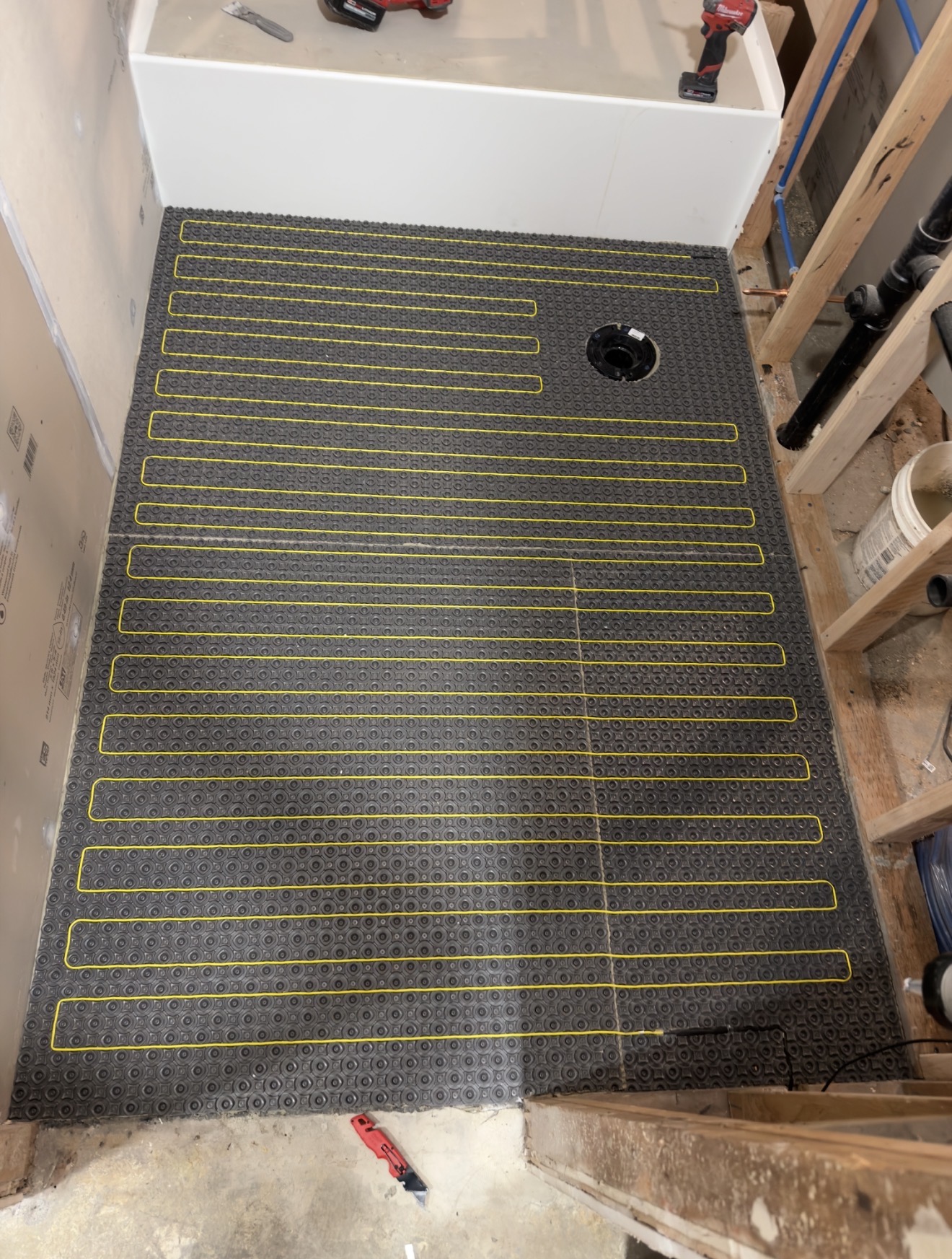 Bathroom floor with radiant heating cable spaced evenly through a heating membrane
