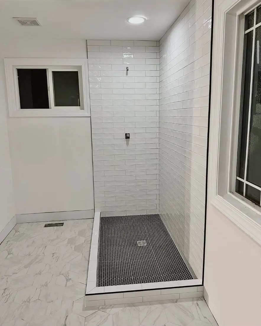 White subway tile shower with black penny tile shower pan