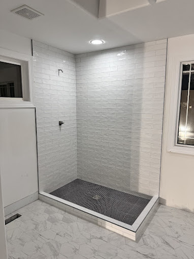 White brick-look tile shower with dark penny tile pan and marble-look floor