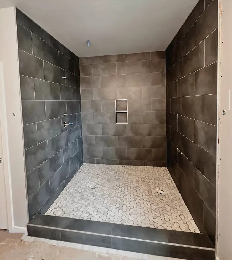 Dark tile shower enclosure with white hexagon mosaic shower floor