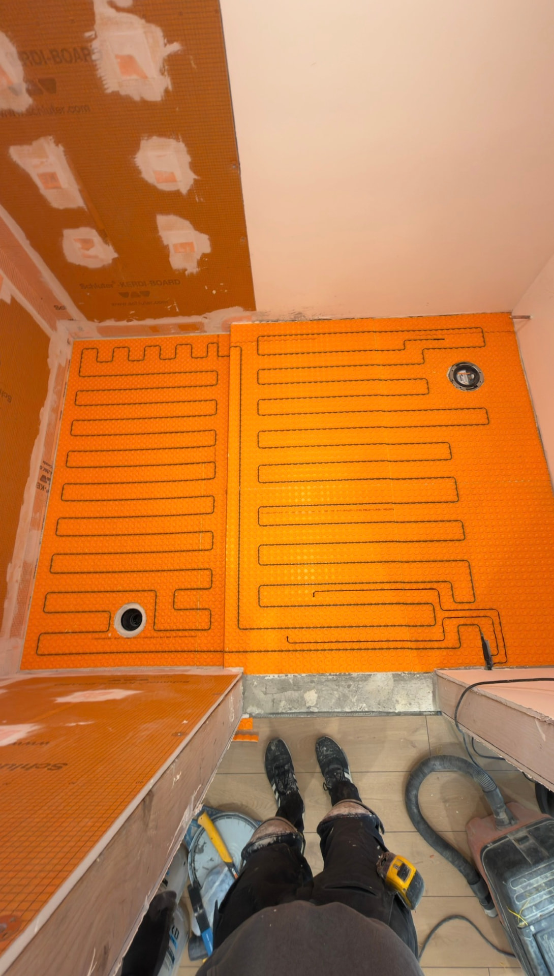Radiant heat cable looped over an orange uncoupling membrane in a bathroom
