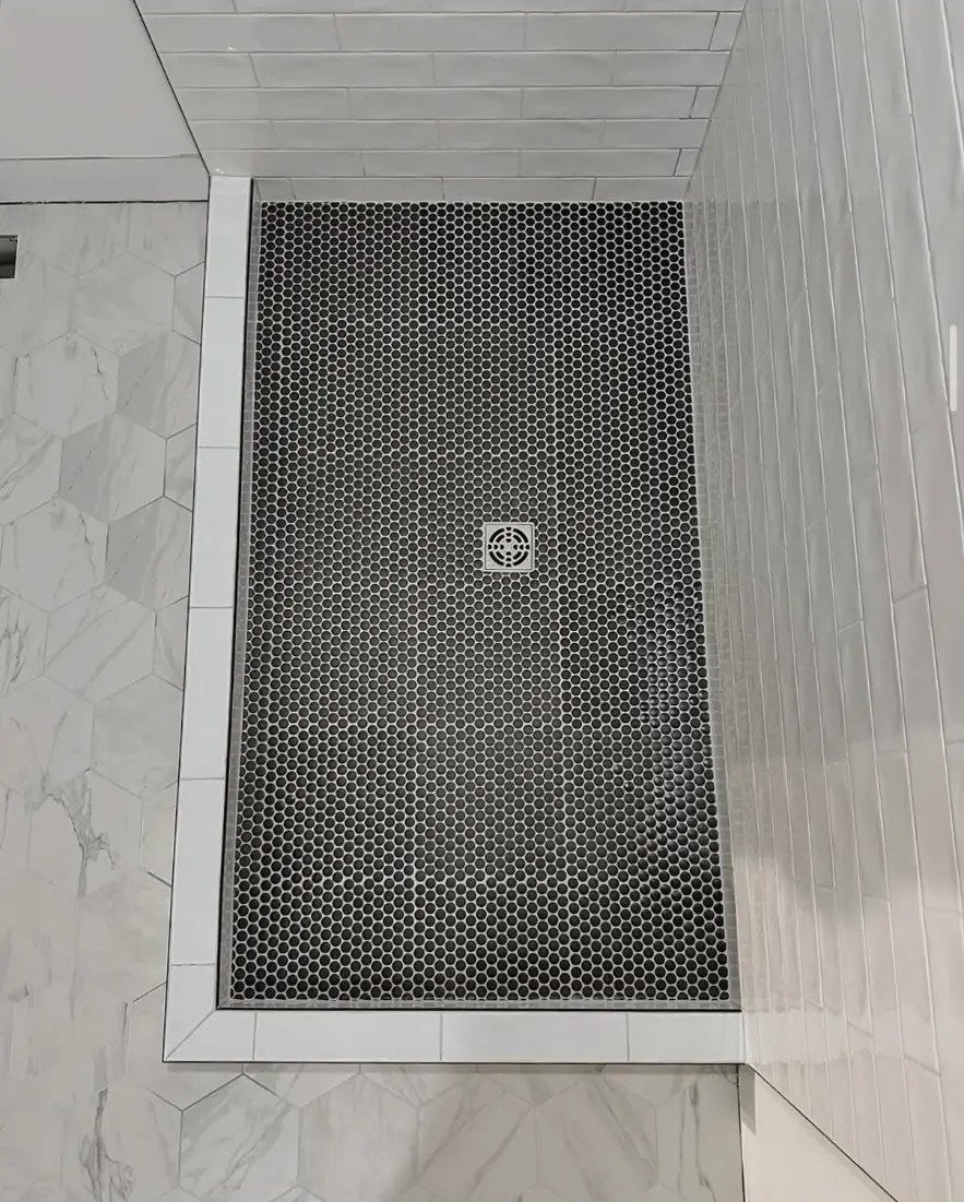 Black penny tile shower pan framed by white subway and hexagon tile
