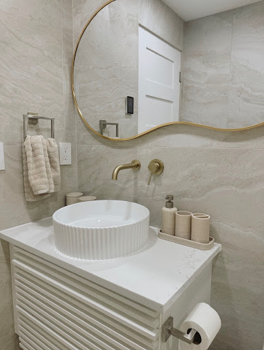 Powder bath with stone-look tile walls, fluted vessel sink and brushed gold wall-mount faucet