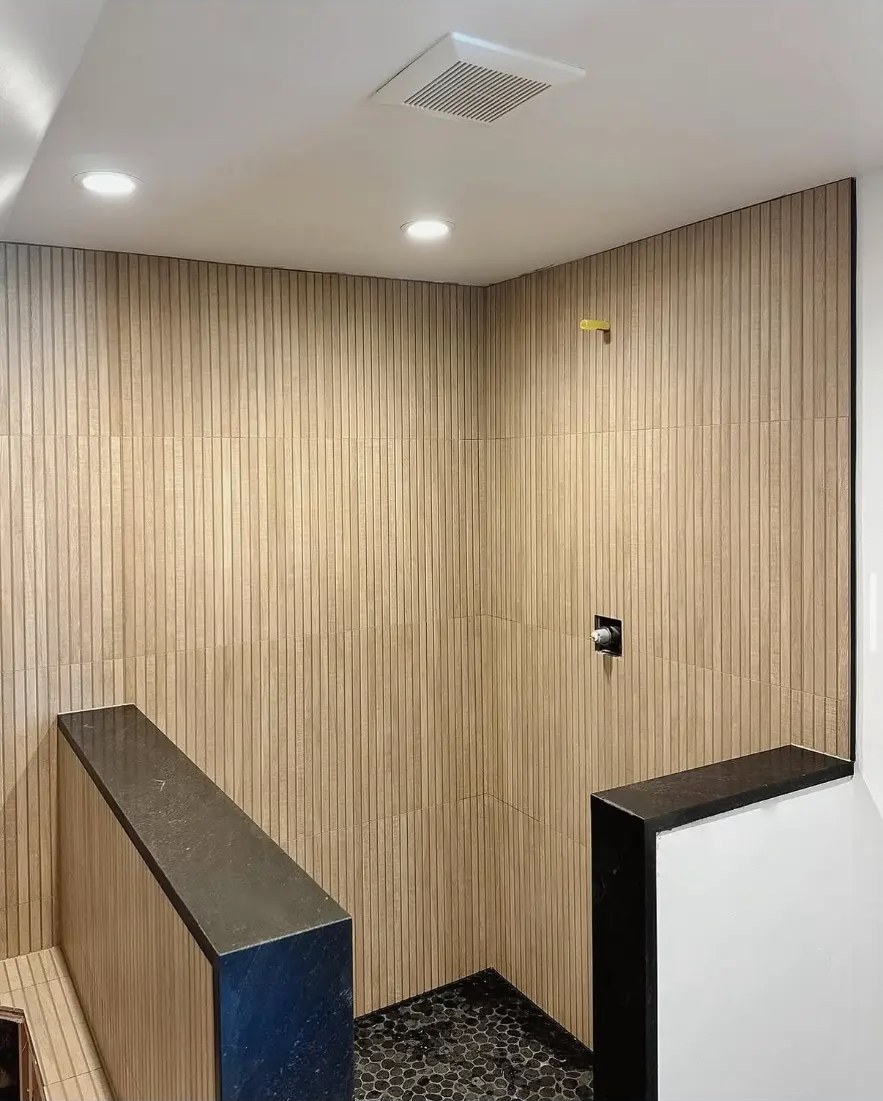 Wood-look vertical tile shower with stone bench and pebble floor