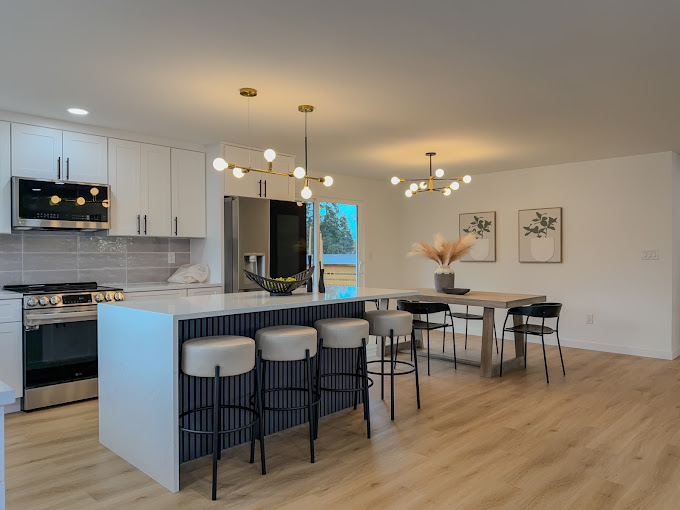 Open-concept kitchen and dining area with waterfall island and gold pendant lighting