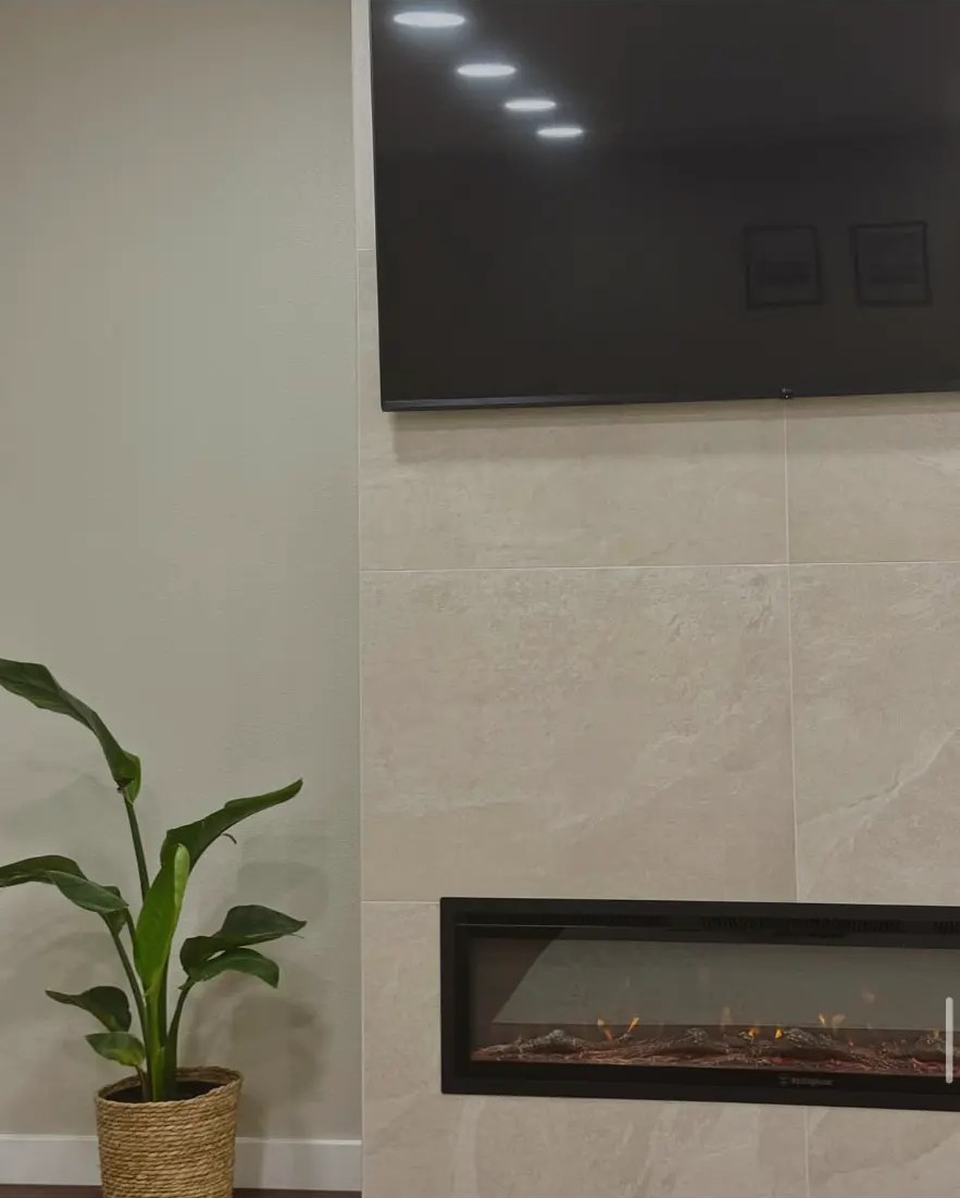 Detail of tiled fireplace surround with linear insert and mounted TV