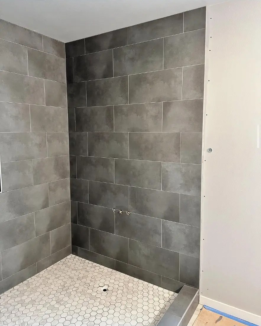 Charcoal large-format tile shower with white hexagon mosaic floor