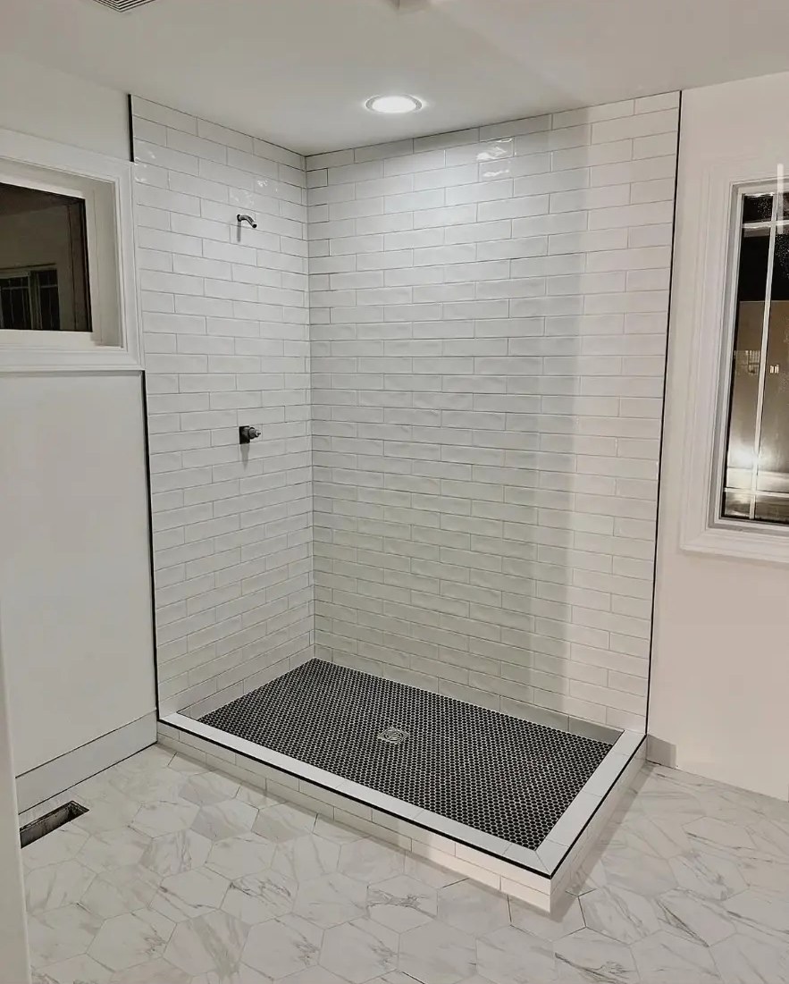Custom walk-in shower with subway tile walls and marble-look floor tile