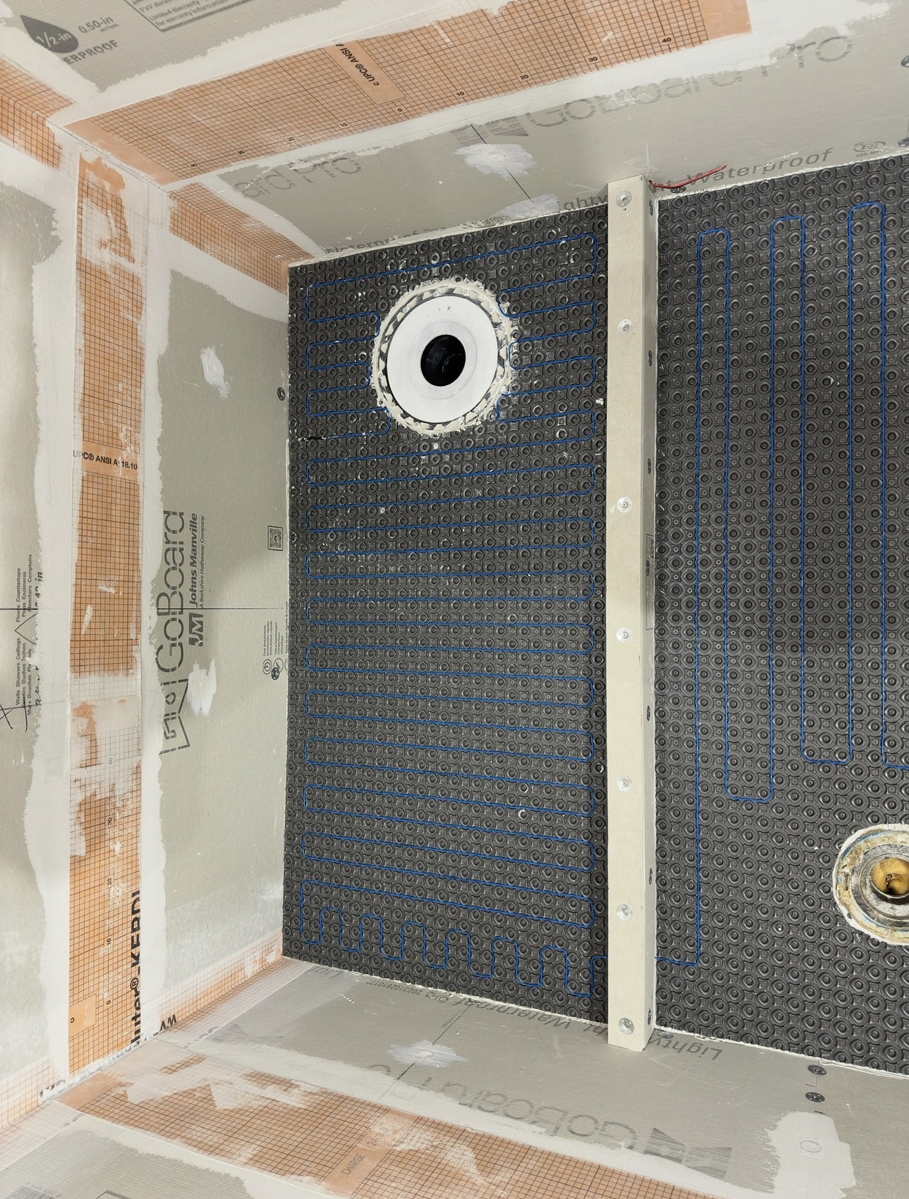 Radiant heating cable installed on shower bench and walls over waterproof board