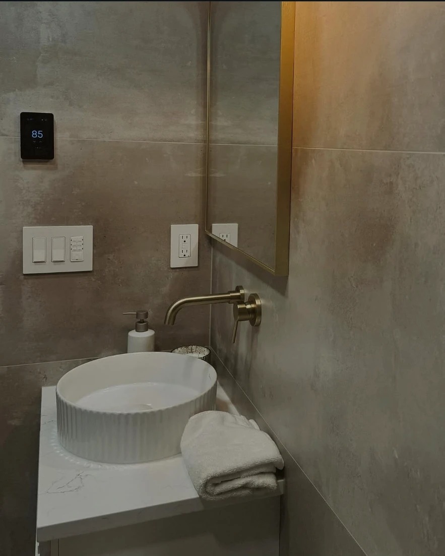 Beige large-format tile bathroom with brushed gold fixtures and fluted vessel sink